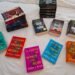Sarah J. Maas Book Collection on A White Plush Bed Scattered Across