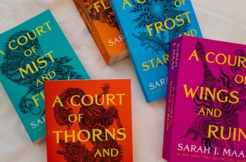 A Court of Thorns and Roses book set on a white bed
